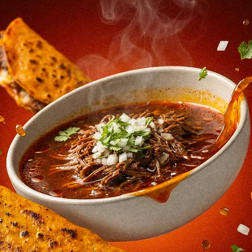 Plato de consomé de birria con cebolla y cilantro